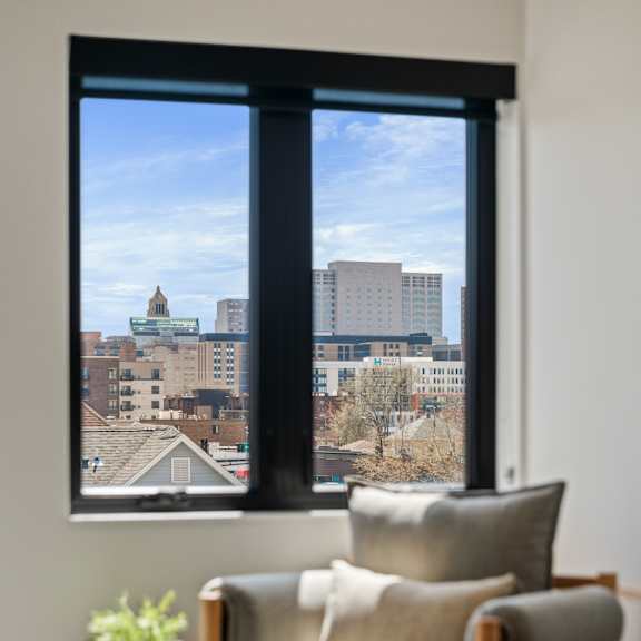 a chair and a table in front of a window with a view of a cityscape.