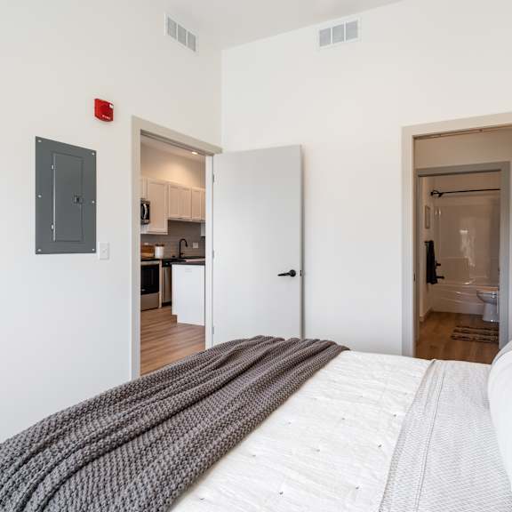 a bedroom with a large bed and a red fire alarm on the wall.