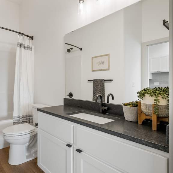 a bathroom with a white toilet and a white tub with a shower curtain.