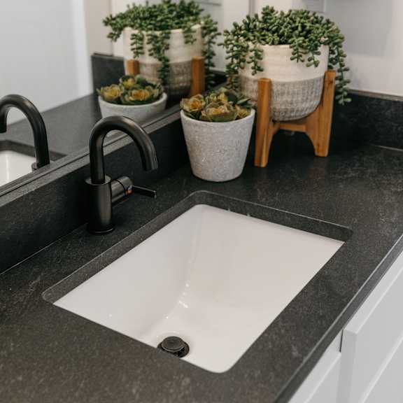 a bathroom sink with a black countertop and a white sink.