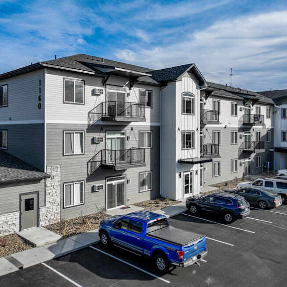 a rendering of a white and black apartment building with cars parked in front