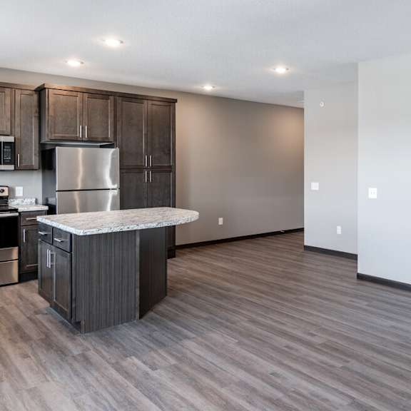 an open kitchen and living room with wood flooring and stainless steel appliances