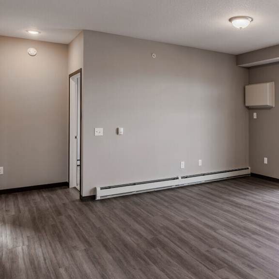 the living room of a new home with a large window and wood flooring