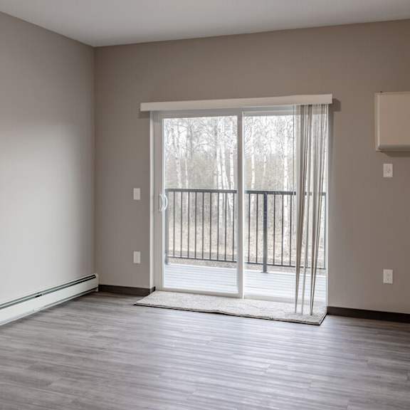 an empty living room with a sliding glass door to a balcony