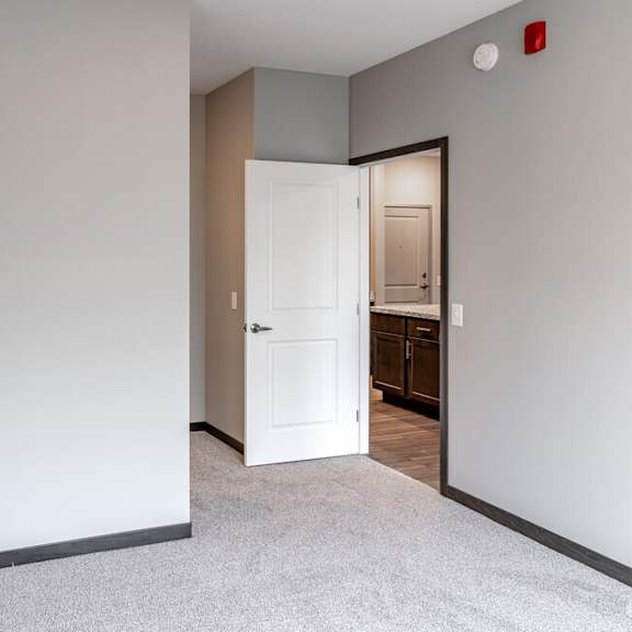 an empty bedroom with a door open to a bathroom