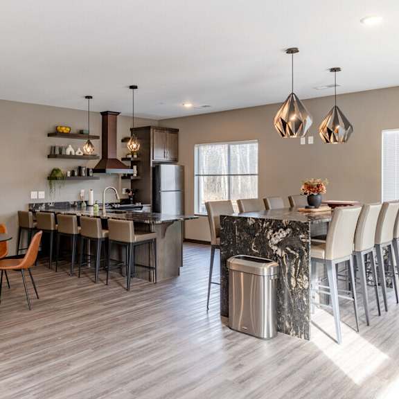 a kitchen with a bar and a dining room with chairs