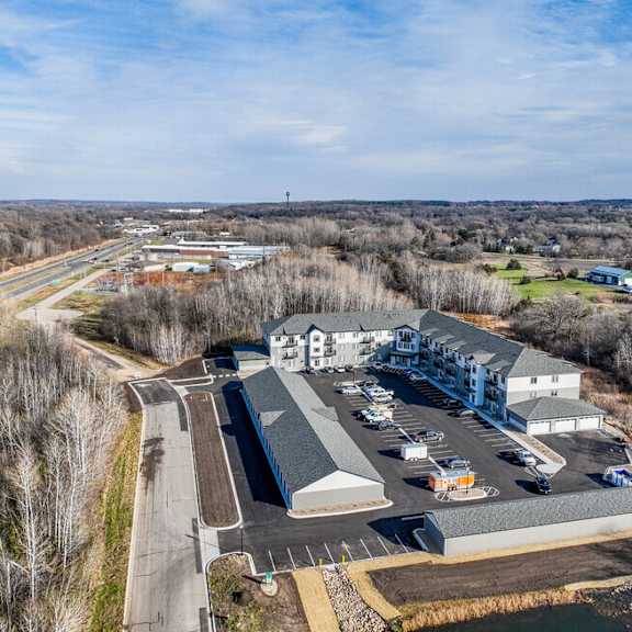 an aerial view of a building and a parking lot with a highway in the background