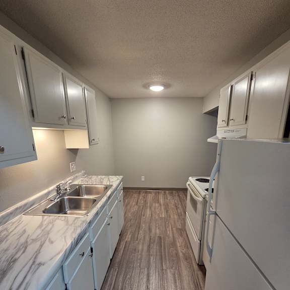 a kitchen with white cabinets and a marble countertop.