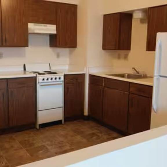 a kitchen with brown cabinets and a white refrigerator.