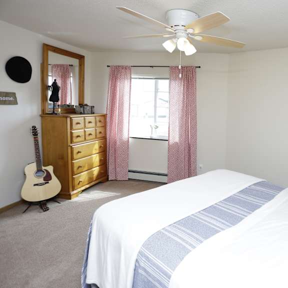 a bedroom with a bed, dresser, and guitar.