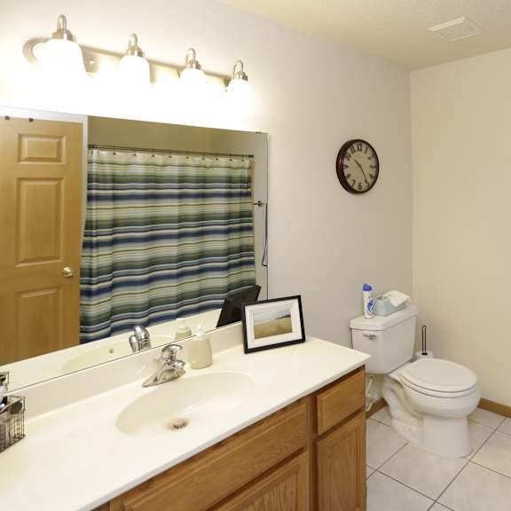 a bathroom with a toilet, sink, mirror, and striped towel.