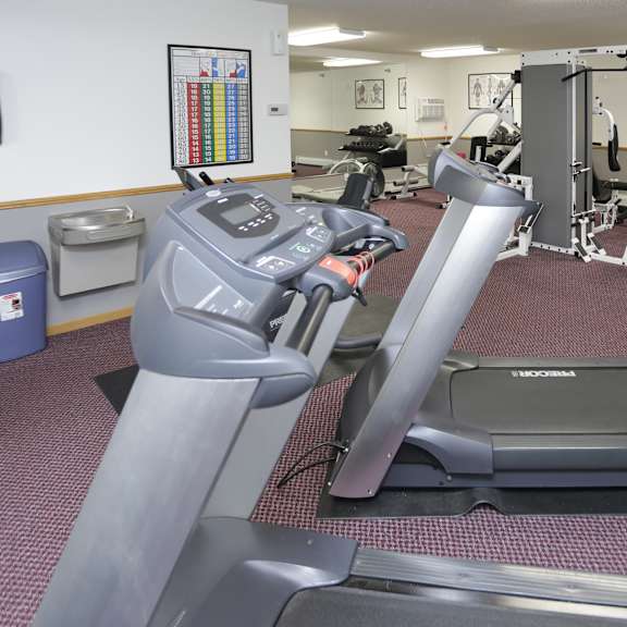 a treadmill and a stationary bike are in a gym.