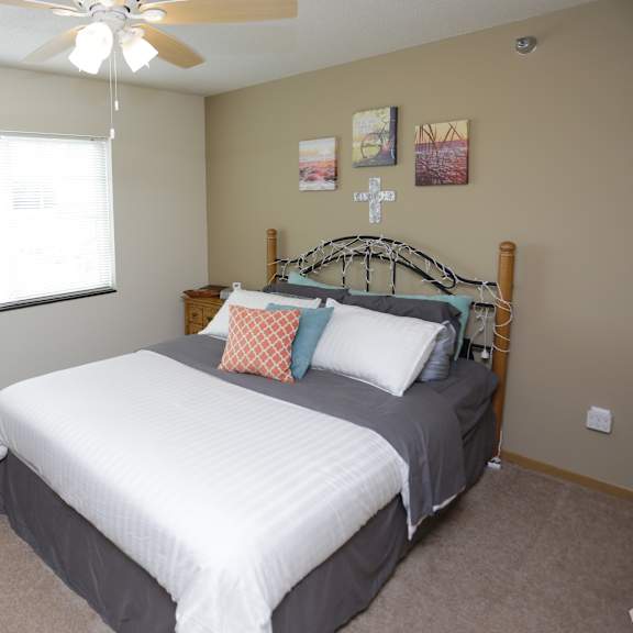 a bedroom with a bed, a ceiling fan, and a guitar.