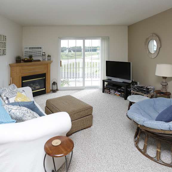 a living room with a white couch, a wooden fireplace, a television, and a rocking chair.