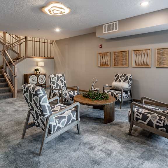 a lobby with a grey carpet and a wooden staircase.