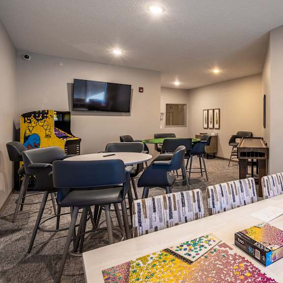 a room with a white table and chairs, a television, and a collection of jigsaw puzzles.