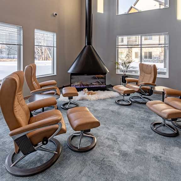 a room with a fireplace and leather chairs.