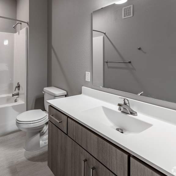 a modern bathroom with a white sink, toilet, and a glass shower stall.