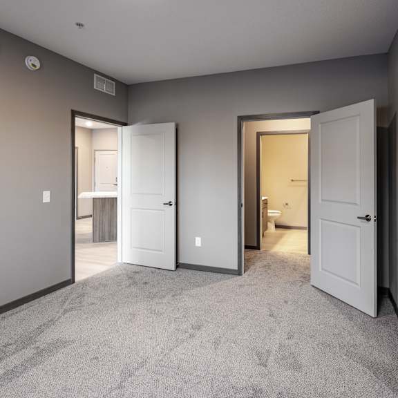 a room with carpeted floor and three open doors.