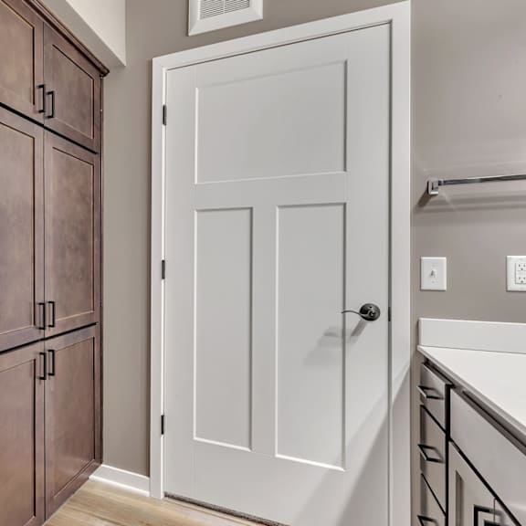 a white door is on the right and a brown cabinet is on the left.