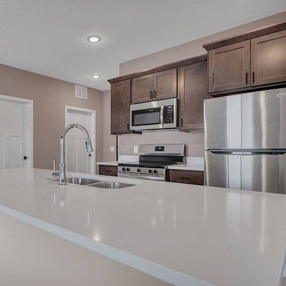 a kitchen with a white countertop and brown cabinets.