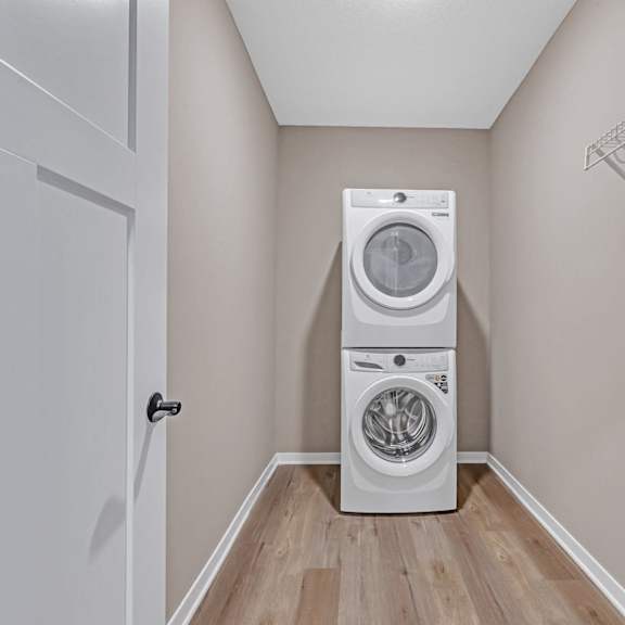 a white dryer and washer are stacked on top of each other in a small laundry room.