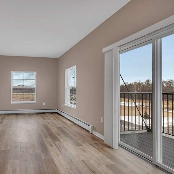a room with wooden floors and a sliding glass door leading to a balcony.