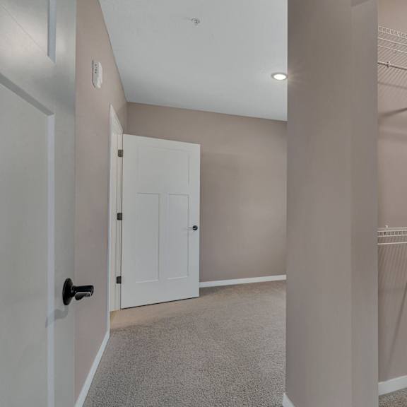 a room with a white door and a wall-mounted closet with shelves.