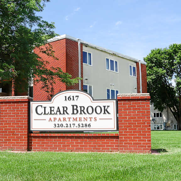 a sign for clear brook apartments is in front of a brick building.