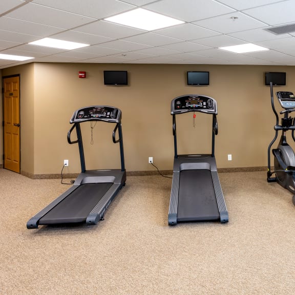 a gym with four treadmills in a room
