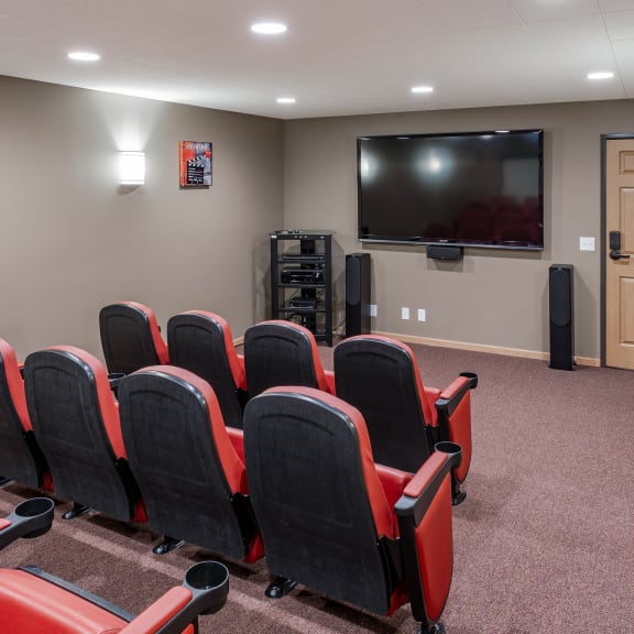 a small theater room with red chairs and a television