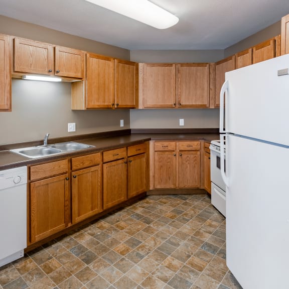 an empty kitchen with white appliances and wooden cabinets