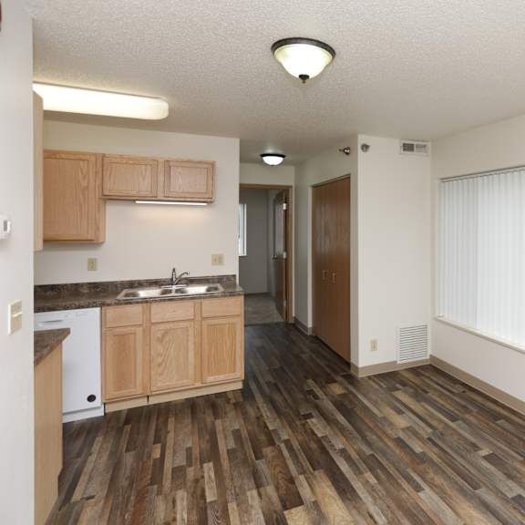 a kitchen with wooden floors and white walls.