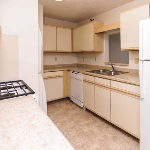 a kitchen with a white refrigerator and beige cabinets.