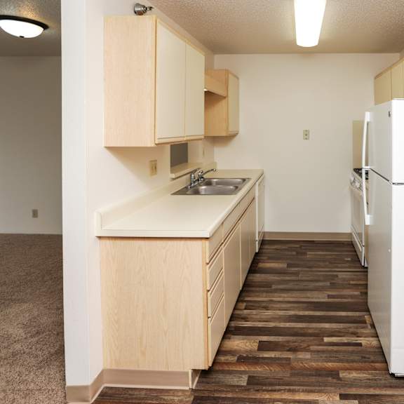 a kitchen with a white fridge and wooden cabinets.