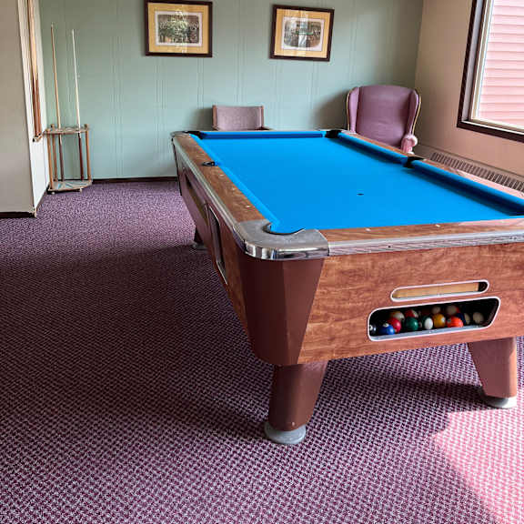 a pool table with a brown side rail and a blue felt cloth.