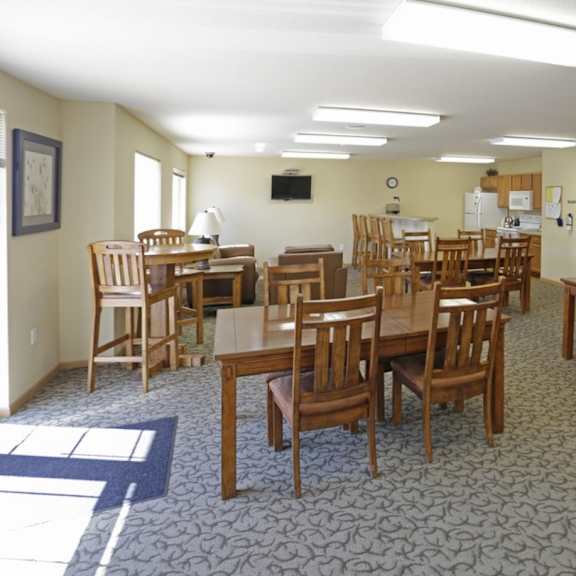 a room with tables and chairs and a tv on the wall.