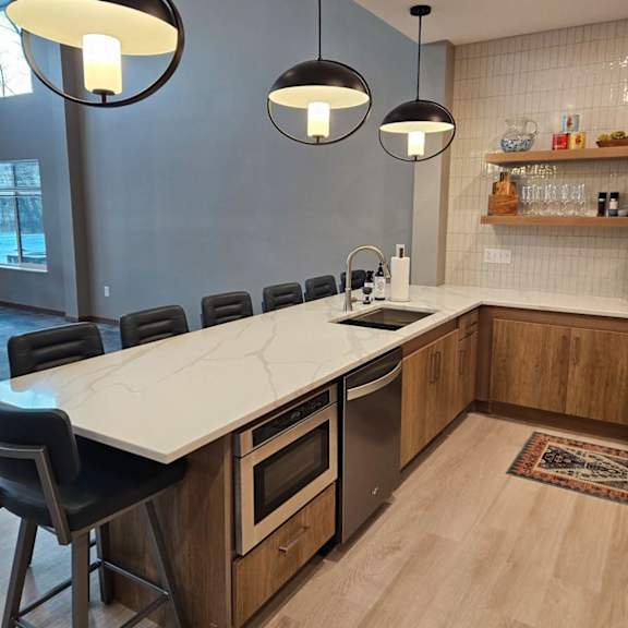 a modern kitchen with a long island and black chairs.