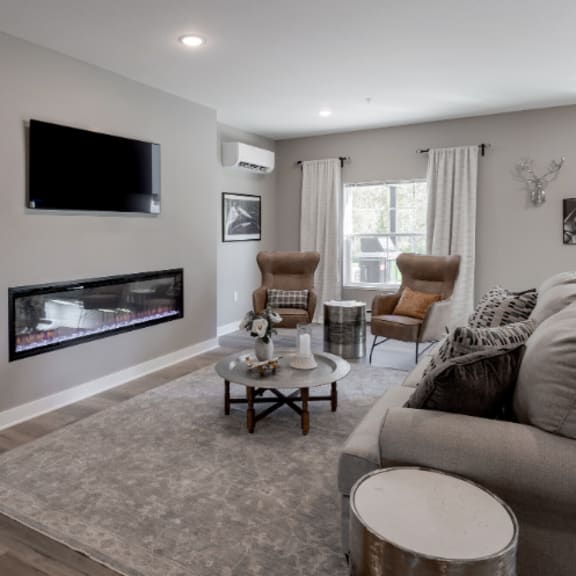 a living room with a grey couch and a television on the wall.