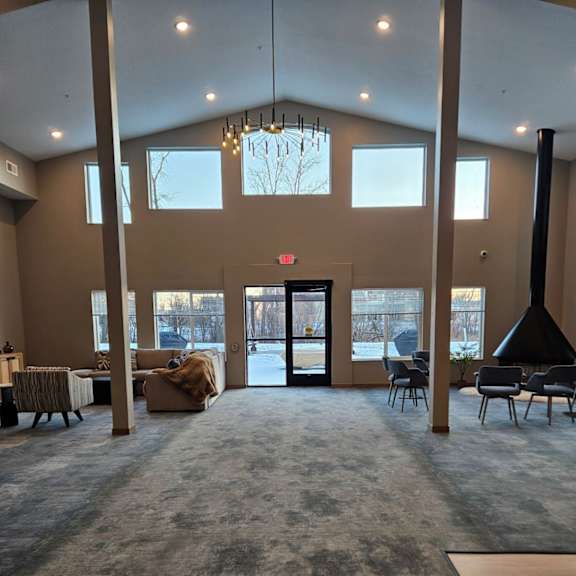 a large room with a grey carpet and a chandelier hanging from the ceiling.