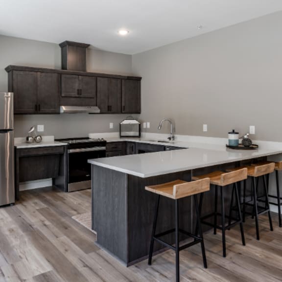 a modern kitchen with a stainless steel refrigerator and wooden flooring.