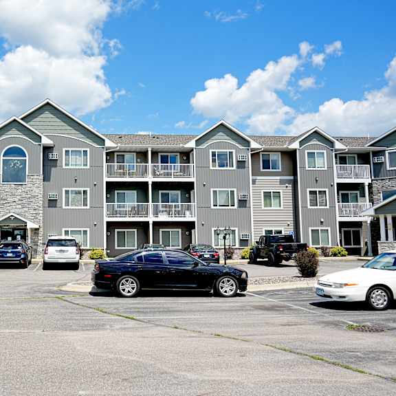 a parking lot in front of a building with cars parked.