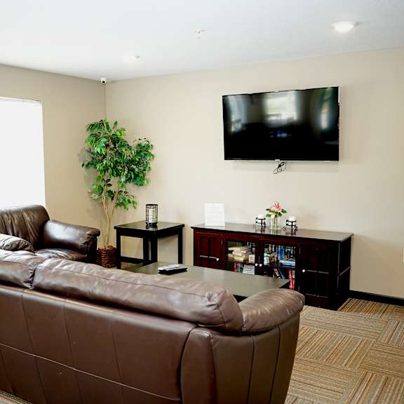 a living room with a brown couch and a flat screen tv mounted on the wall.