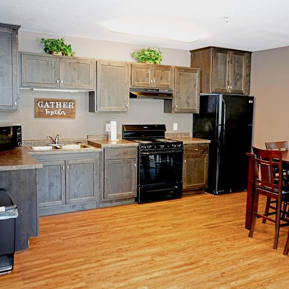 a kitchen with wooden floors and a black refrigerator.