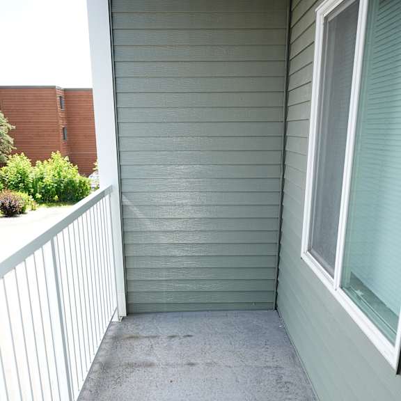 a grey concrete porch with a white railing and a window.