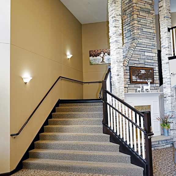 a staircase with a stone pillar and a fireplace in the background.