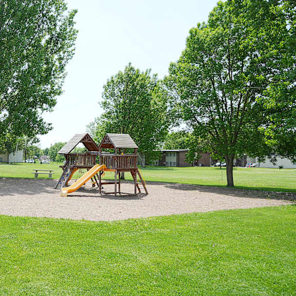 a playground with a yellow slide and a brown wooden structure.