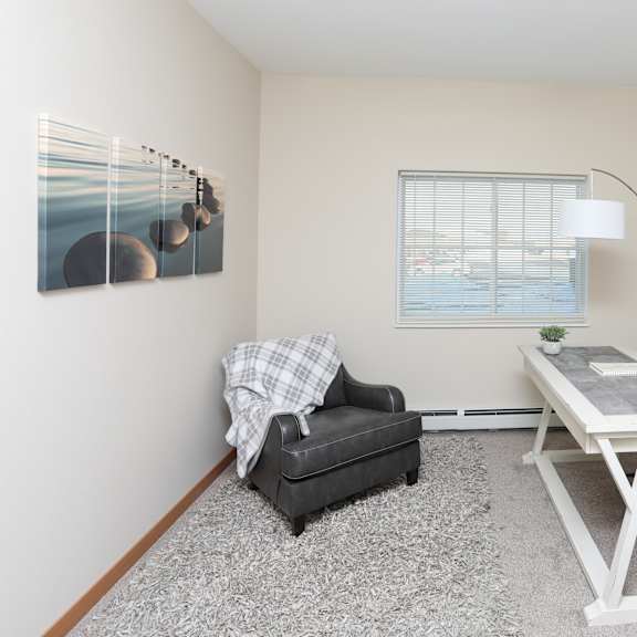 a room with a table, chair, and a painting on the wall.