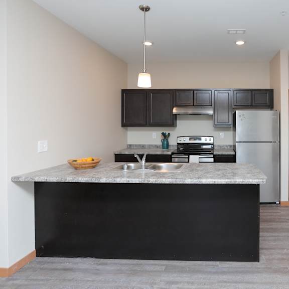 a kitchen with a black countertop and stainless steel appliances.