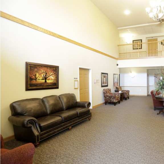 a living room with a black leather couch and a painting of a tree on the wall.
